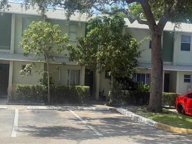 A two-story townhouse exterior features light-colored siding, green accents, and assigned parking spaces — 795 Crystal Lake Drive # 795, Deerfield Beach FL 33064, DEERFIELD BEACH, FL