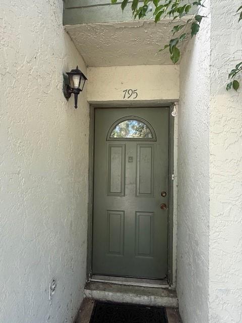 A green front door with a small window is set in a stucco entryway — 795 Crystal Lake Drive # 795, Deerfield Beach FL 33064, DEERFIELD BEACH, FL