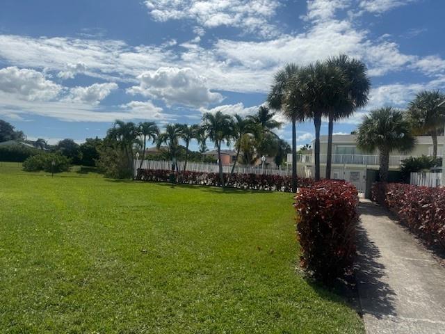 A grassy lawn leads to a white fence, palm trees, and a two-story building — 795 Crystal Lake Drive # 795, Deerfield Beach FL 33064, DEERFIELD BEACH, FL