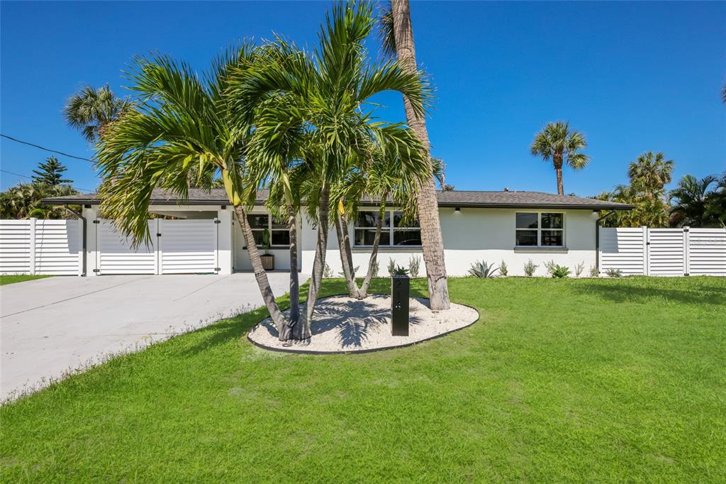 A single-story white house with a palm tree-filled front yard and a concrete driveway — 214 85TH STREET, HOLMES BEACH, FL