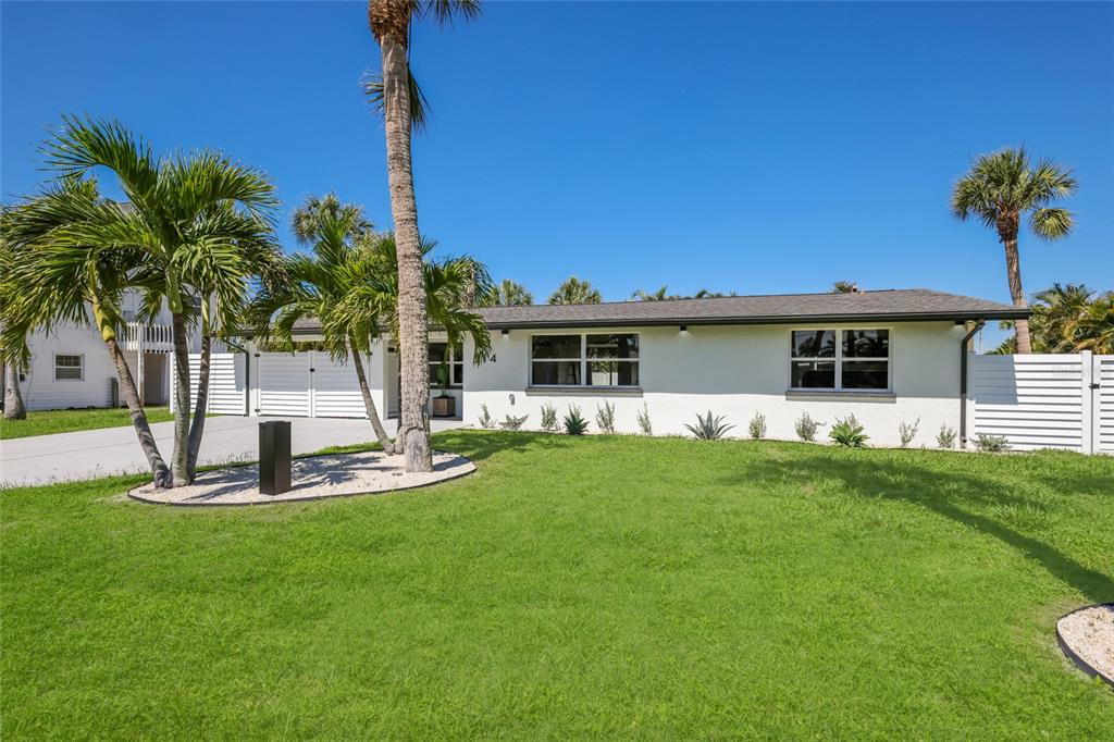 A single-story white house with a palm tree in the front yard under a blue sky — 214 85TH STREET, HOLMES BEACH, FL