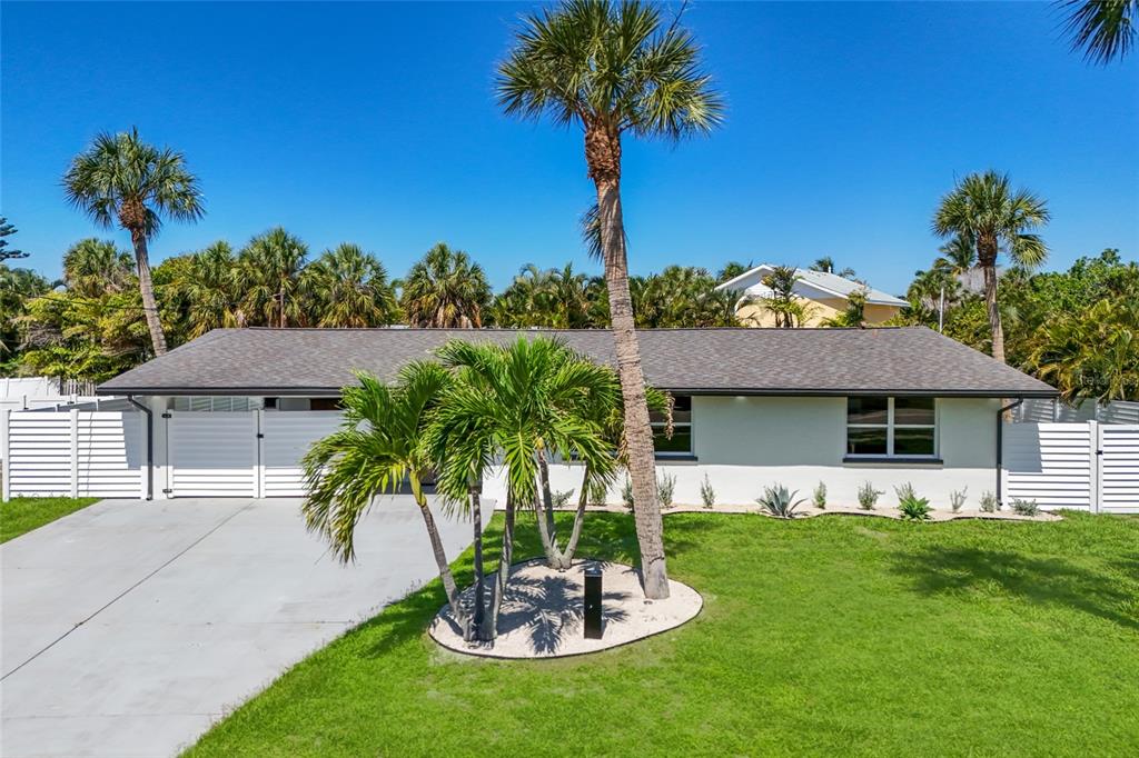A single-story house with a white exterior, gray roof, and palm trees in the yard — 214 85TH STREET, HOLMES BEACH, FL