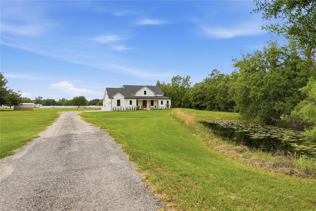 A white house with a dark roof sits at the end of a gravel driveway — 4730 QUAIL ROOST ROAD, ST CLOUD, FL