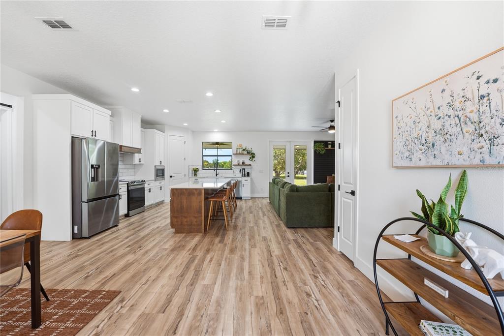 An open-concept kitchen and living area features white cabinetry, a wood-toned island, and wood-look flooring — 4730 QUAIL ROOST ROAD, ST CLOUD, FL