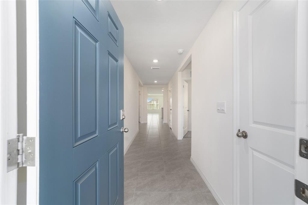 A view from an open blue front door into a tiled hallway with white walls — 8856 SW 49TH CIRCLE, OCALA, FL
