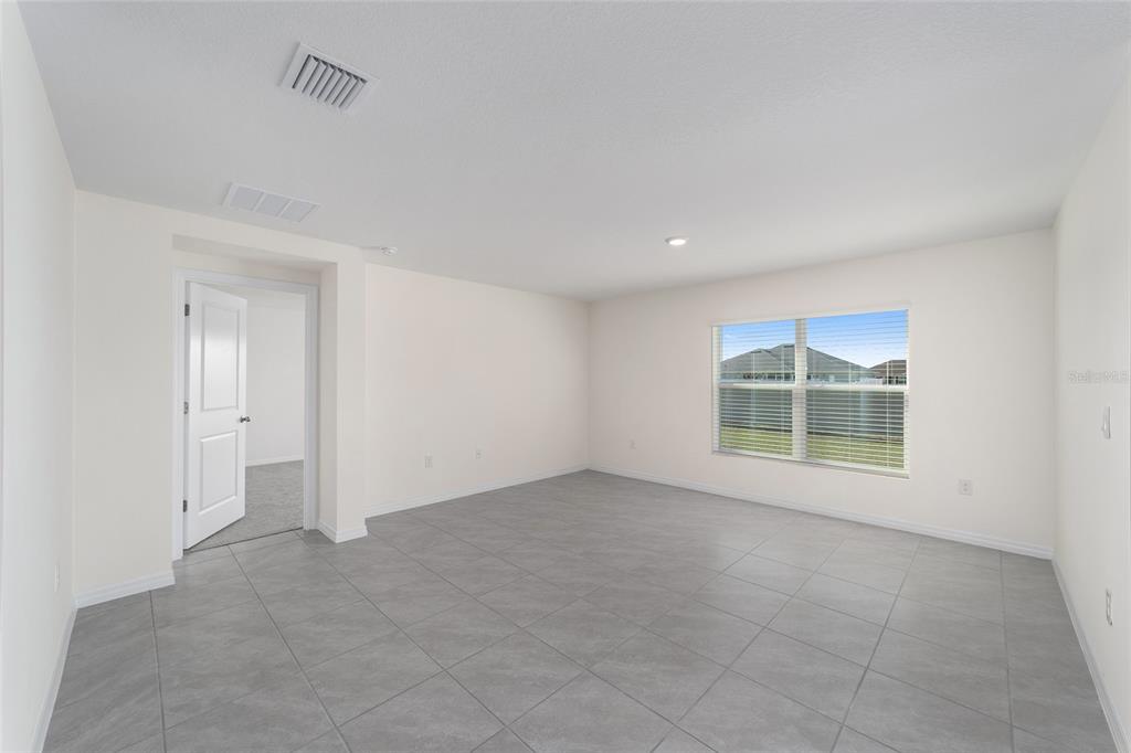 An empty room with light-colored walls, gray tile flooring, and a window overlooking a neighborhood — 8856 SW 49TH CIRCLE, OCALA, FL