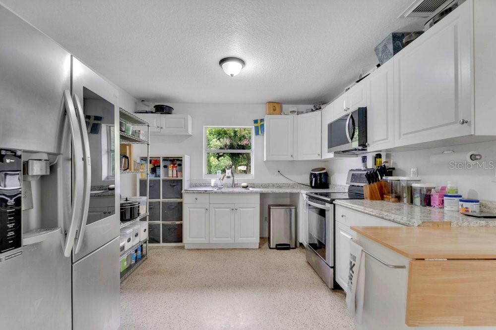 A kitchen with white cabinets, stainless steel appliances, granite countertops, and a wire storage rack — 851 E UNIVERSITY AVENUE, ORANGE CITY, FL