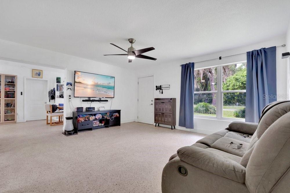 A living room features a wall-mounted television, a ceiling fan, and a large window — 851 E UNIVERSITY AVENUE, ORANGE CITY, FL