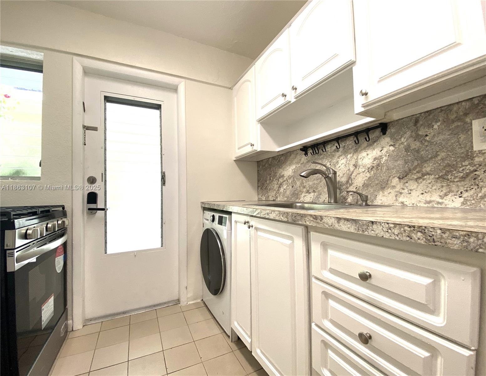 A kitchen features white cabinets, a granite countertop, a sink, and a built-in washing machine — 932 Euclid Ave # 2, Miami Beach FL 33139, MIAMI BEACH, FL