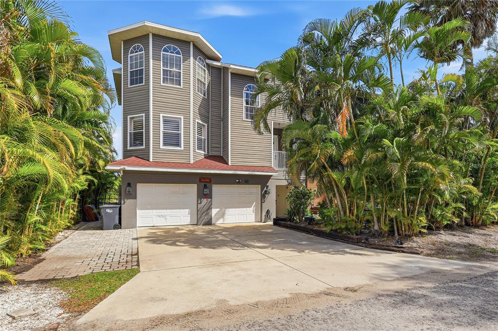 A three-story house with gray siding, a two-car garage, and surrounding palm trees — 28 MICHIANA DRIVE, TERRA CEIA, FL