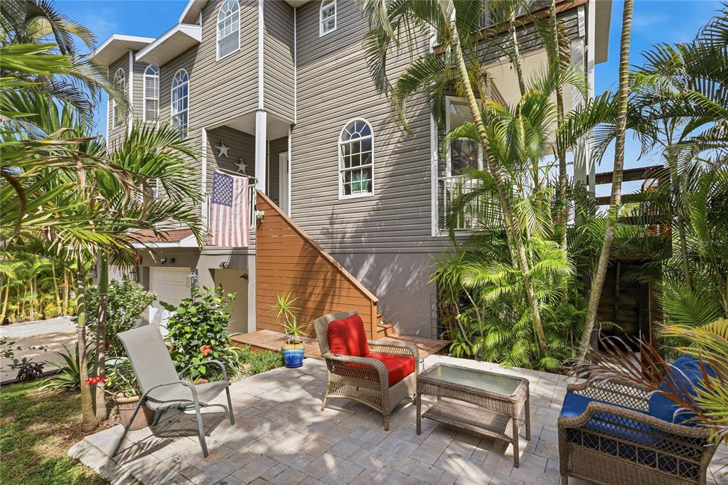 A patio with wicker furniture sits in front of a multi-story house with gray siding — 28 MICHIANA DRIVE, TERRA CEIA, FL