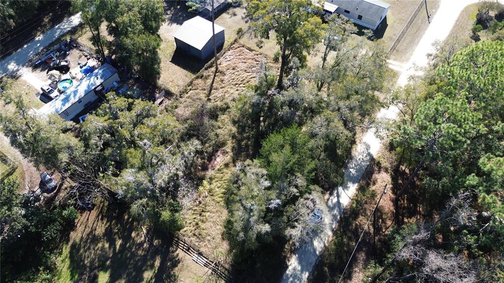 An aerial view shows a wooded residential lot with a driveway and nearby houses — 145 NW 134TH COURT, OCALA, FL