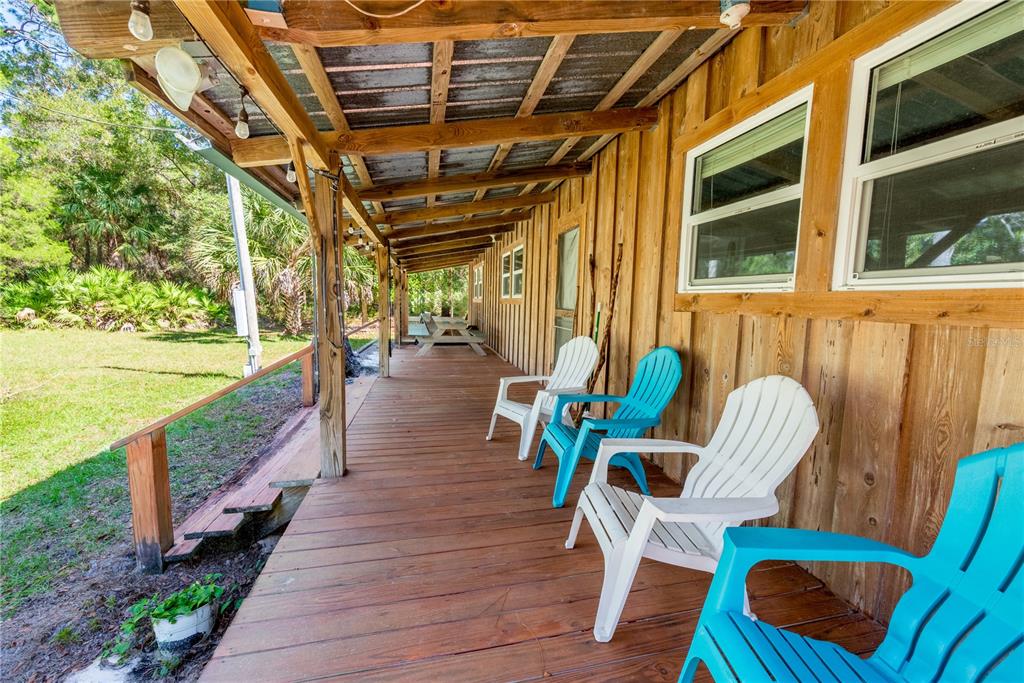A wooden porch with a metal roof features several plastic chairs and a picnic table — 6550 SW 100TH COURT, CEDAR KEY, FL, FL