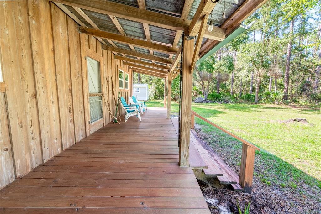 A wooden porch with a metal roof overlooks a grassy yard and wooded area — 6550 SW 100TH COURT, CEDAR KEY, FL, FL