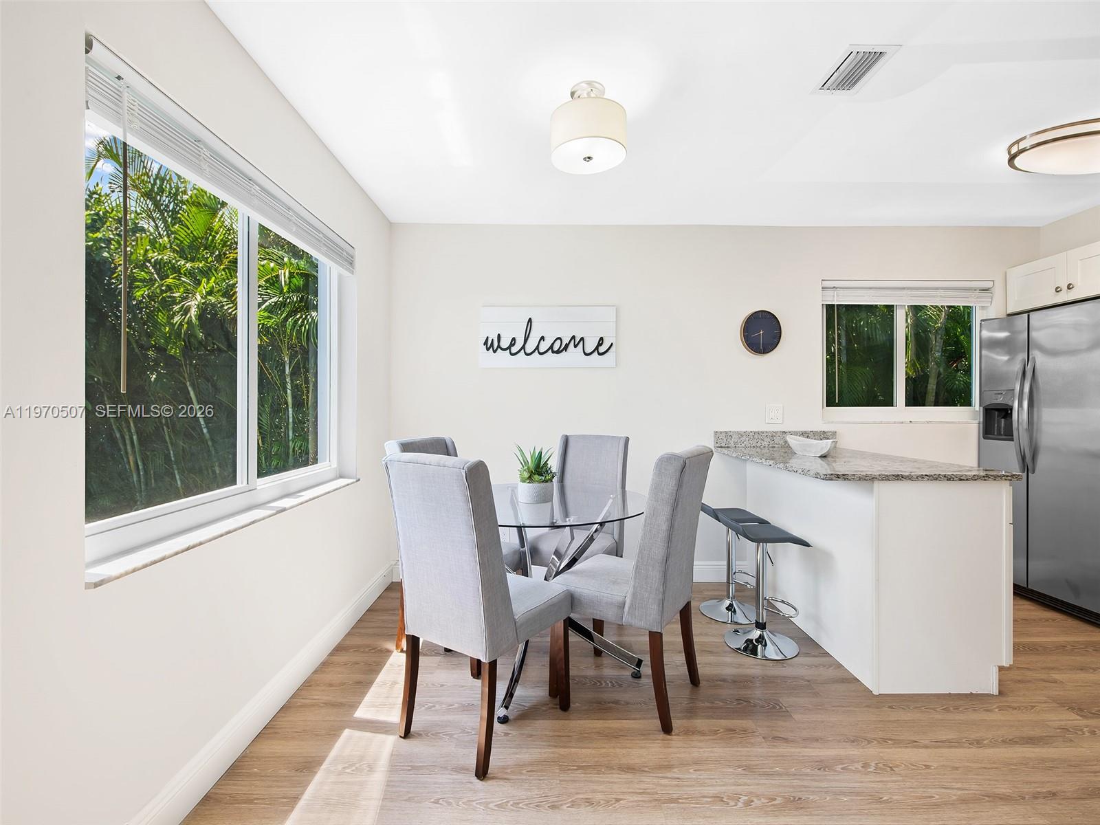 A dining area features a glass table, four grey chairs, and a kitchen breakfast bar — 3405 Norfolk St, Pompano Beach FL 33062, POMPANO BEACH, FL