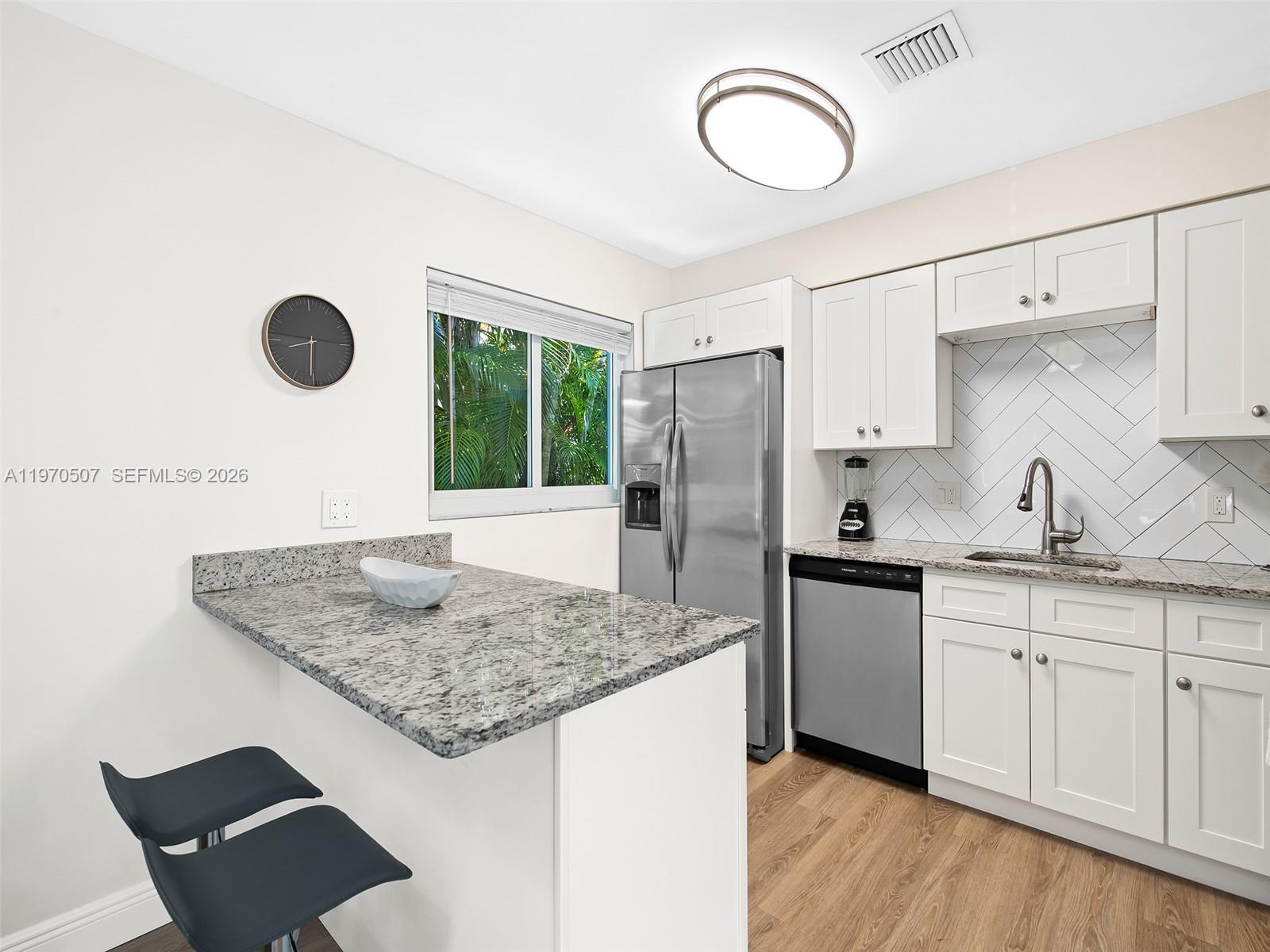 A kitchen features white cabinets, granite countertops, stainless steel appliances, and a breakfast bar — 3405 Norfolk St, Pompano Beach FL 33062, POMPANO BEACH, FL