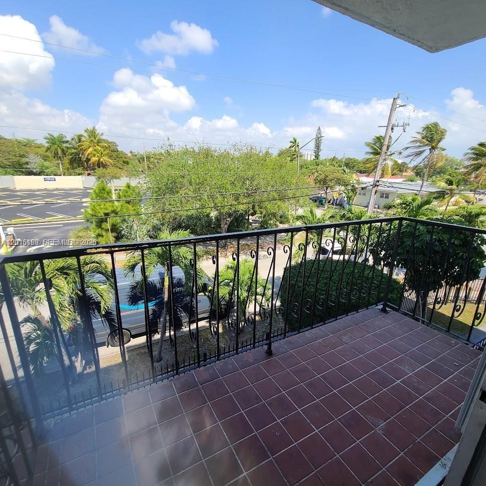 A tiled balcony features a black metal railing overlooking a street, trees, and parking lot — 2500 SW 6th St # 303, Miami FL 33135, MIAMI, FL
