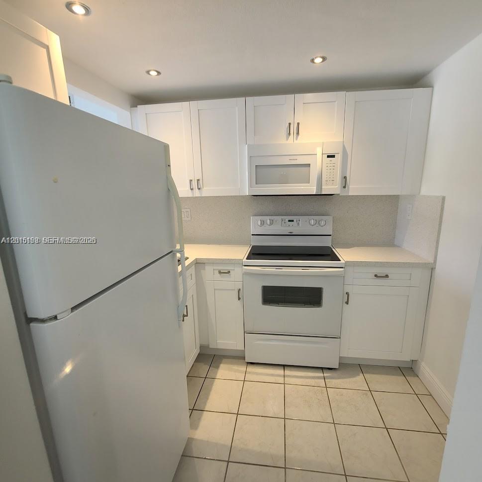 A small kitchen features white cabinets, white appliances, and light-colored tile flooring — 2500 SW 6th St # 303, Miami FL 33135, MIAMI, FL