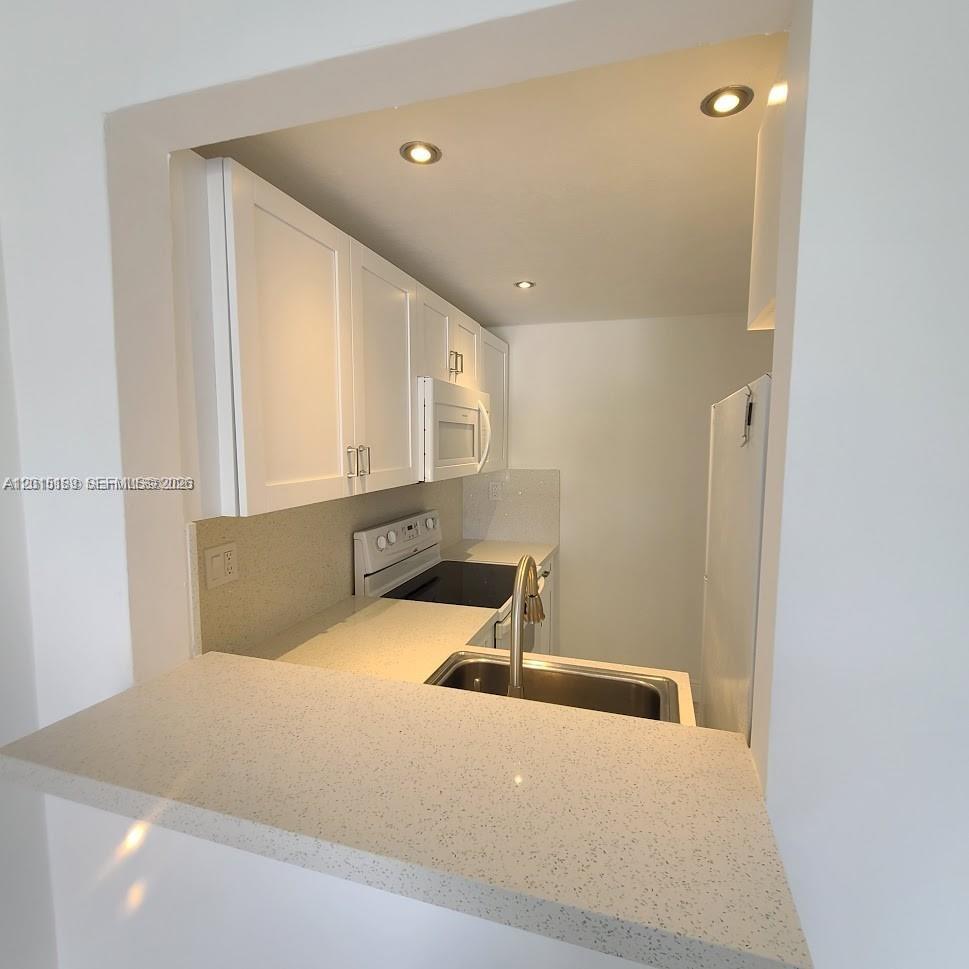 A kitchen features white cabinets, light-colored countertops, a sink, and a stove — 2500 SW 6th St # 303, Miami FL 33135, MIAMI, FL