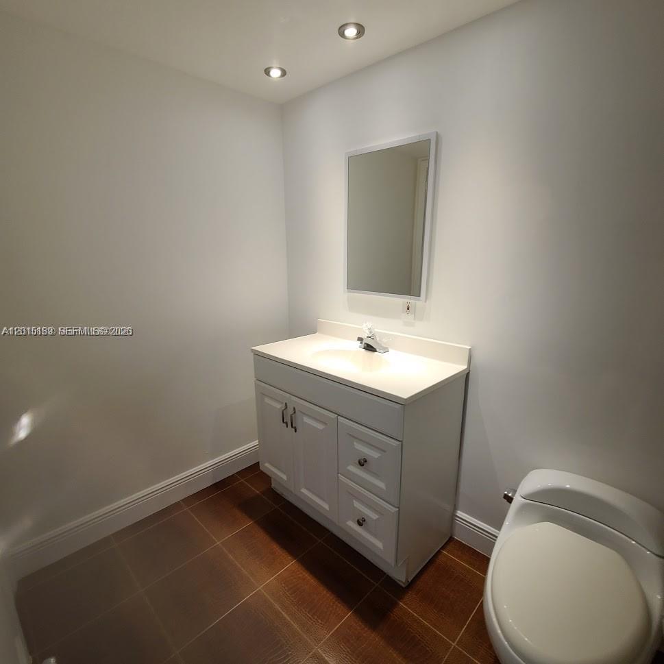 A bathroom features a white vanity, a mirror, and a toilet on brown tile flooring — 2500 SW 6th St # 303, Miami FL 33135, MIAMI, FL