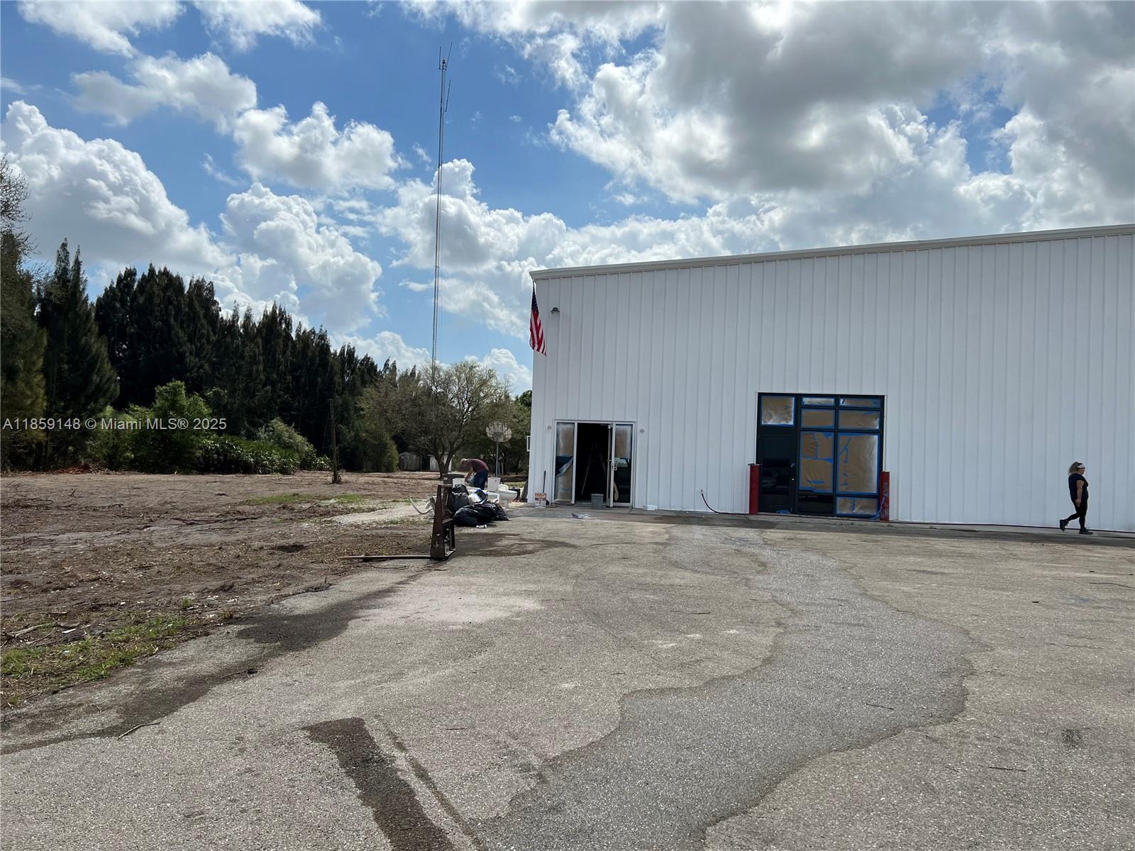 A white metal warehouse building stands next to a dirt lot under a cloudy sky — 14961 SR W78, Moore Haven FL 33471, MOORE HAVEN, FL
