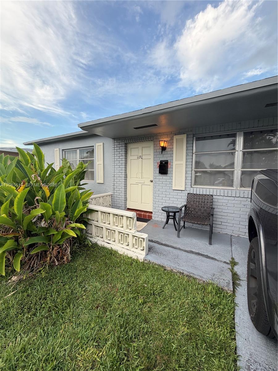 A gray brick house exterior features a light-colored front door, a small porch, and landscaping — 1170 NW 66th Ter, Margate FL 33063, MARGATE, FL