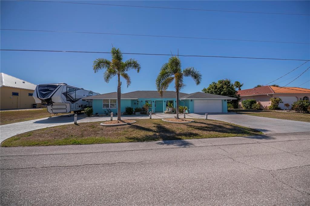 A turquoise single-story house with a two-car garage and a large RV parked outside — 121 SINCLAIR STREET SE, PORT CHARLOTTE, FL