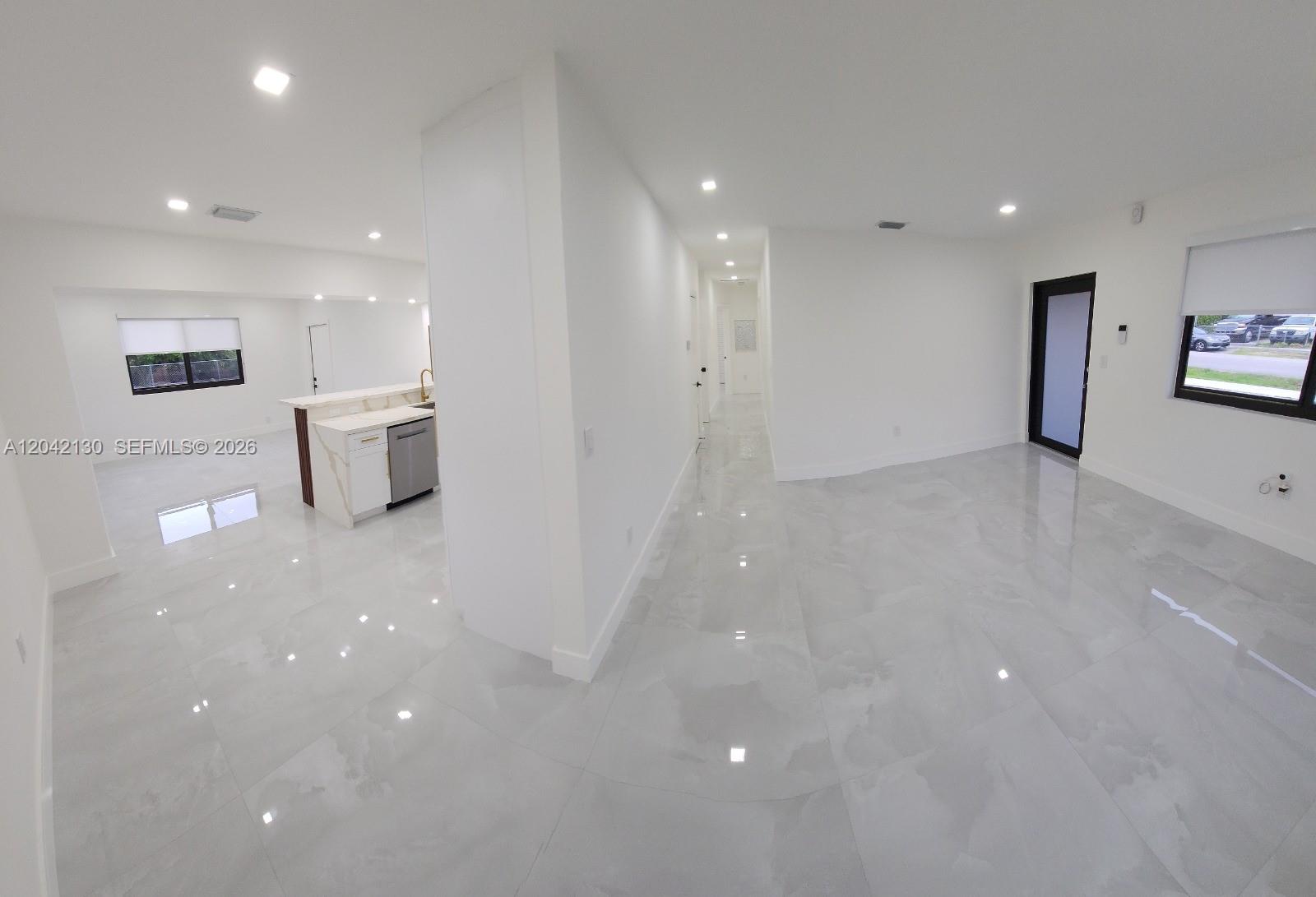 A bright, open-concept living area features white walls, glossy tile flooring, and a modern kitchen — 19721 SW 114th Pl, Miami FL 33157, MIAMI, FL