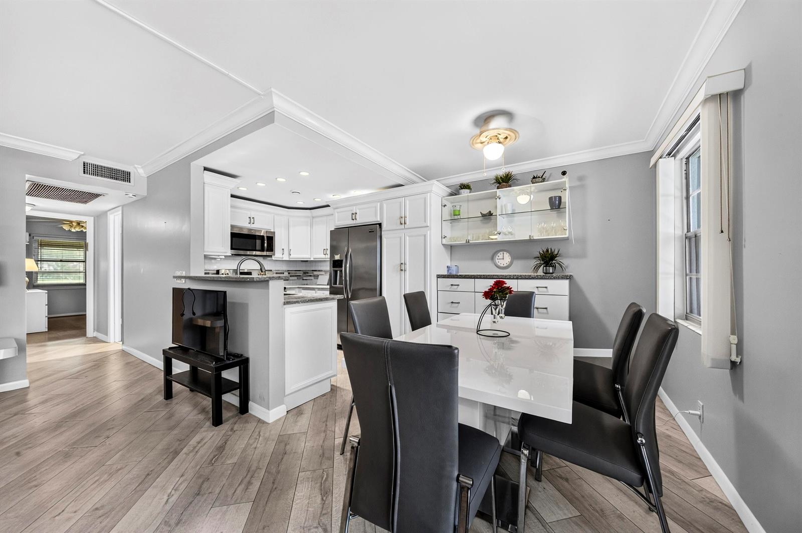 A dining area with a white table and chairs sits adjacent to a modern kitchen — 1039 Berkshire B # 1039, Deerfield Beach FL 33442, DEERFIELD BEACH, FL