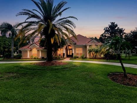 A single-story house with a tile roof and palm trees at dusk — 18655 AVENUE CAPRI, LUTZ, FL