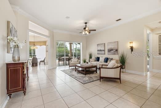 A bright living room features tile flooring, a ceiling fan, and sliding glass doors to a patio — 18655 AVENUE CAPRI, LUTZ, FL
