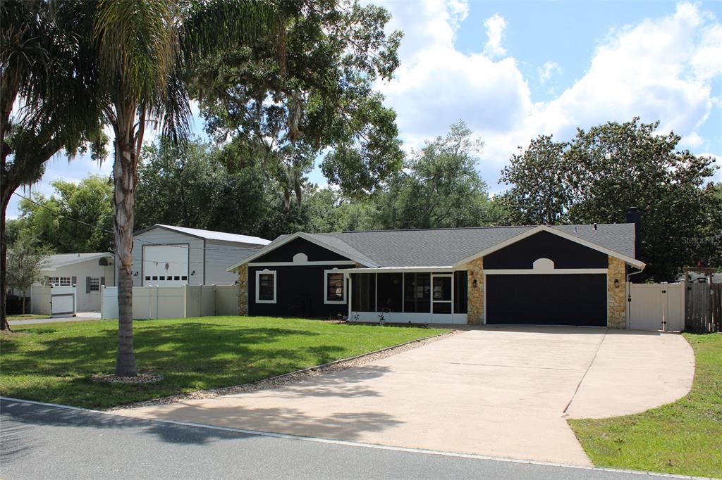 A single-story house with a dark exterior, stone accents, and a detached garage — 27627 LOIS DRIVE, TAVARES, FL