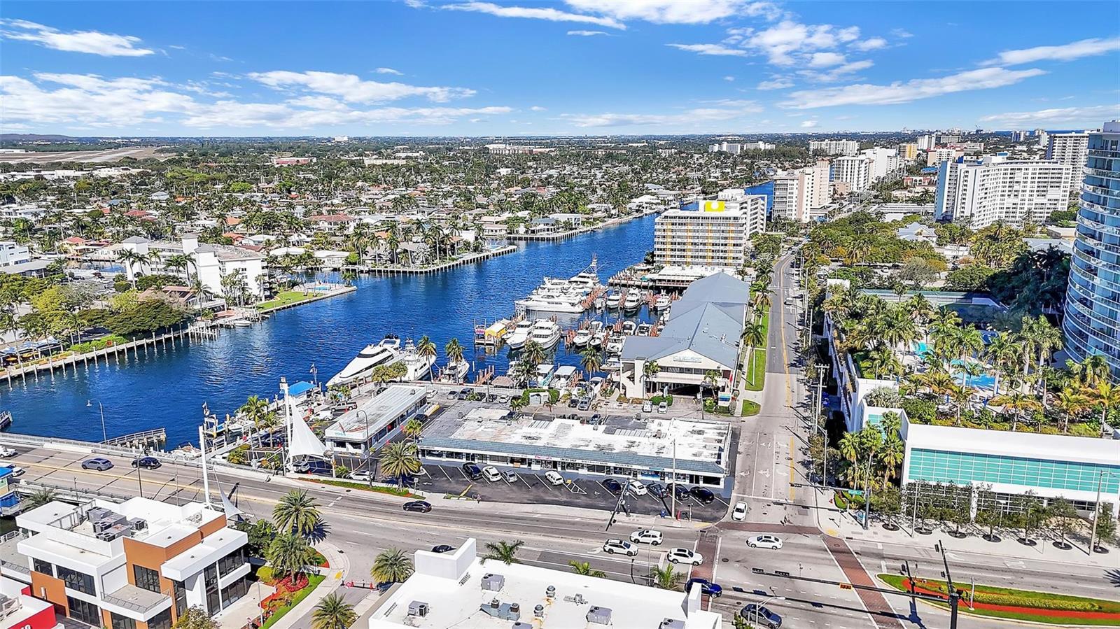 An aerial view shows a marina, a waterway, surrounding buildings, and a coastal city landscape — 3165 E Atlantic Boulevard, Pompano Beach FL 33062, POMPANO BEACH, FL