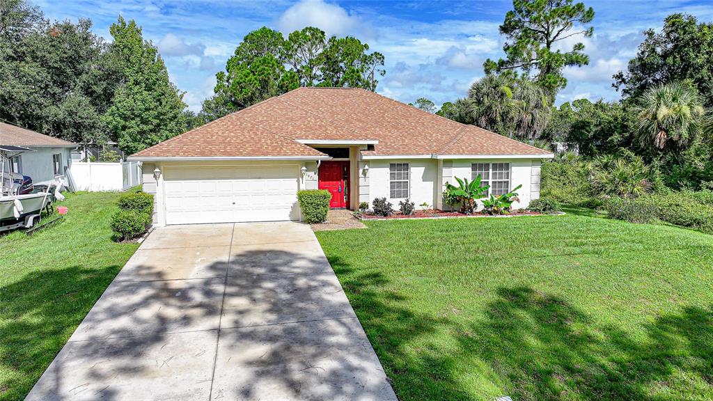 A single-story house with a white garage, red front door, and a brown shingled roof — 1471 PRAIRIE TERRACE, NORTH PORT, FL