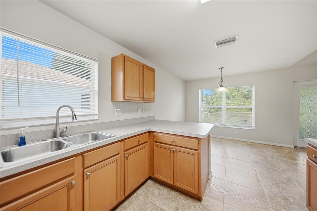 A kitchen with light wood cabinets, gray countertops, a double sink, and tile flooring — 1471 PRAIRIE TERRACE, NORTH PORT, FL