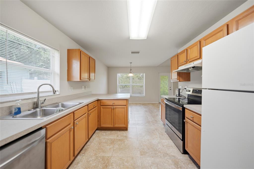 A kitchen features light wood cabinets, laminate countertops, stainless steel appliances, and tile flooring — 1471 PRAIRIE TERRACE, NORTH PORT, FL