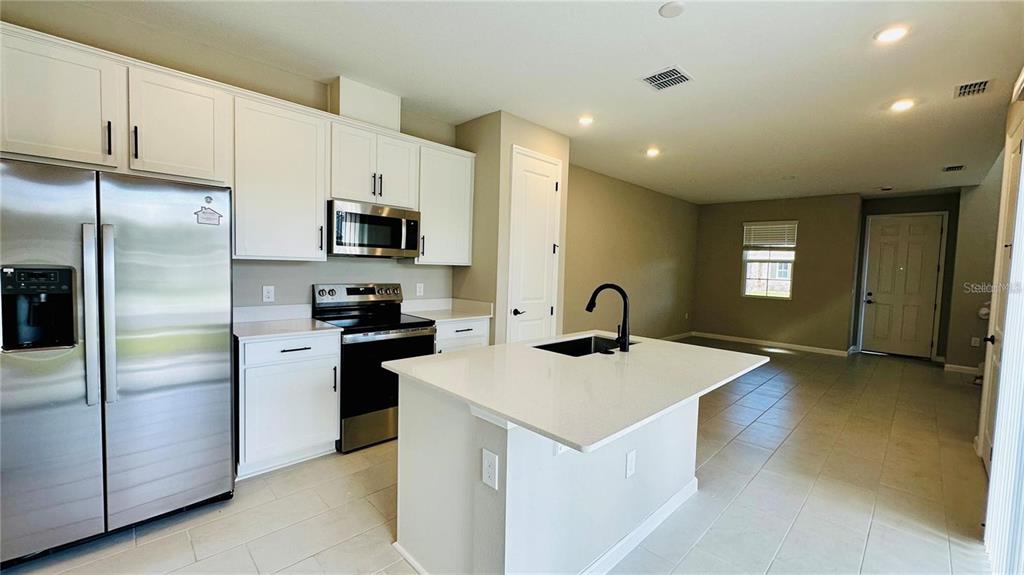 A two-story suburban house with beige siding and a front lawn under a blue sky — 1528 ERIN BREEZE LANE, KISSIMMEE, FL
