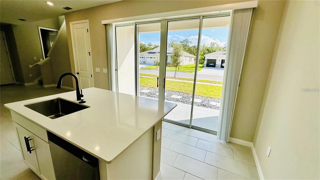 A covered front porch features a dark gray door, stone veneer siding, and a window — 1528 ERIN BREEZE LANE, KISSIMMEE, FL