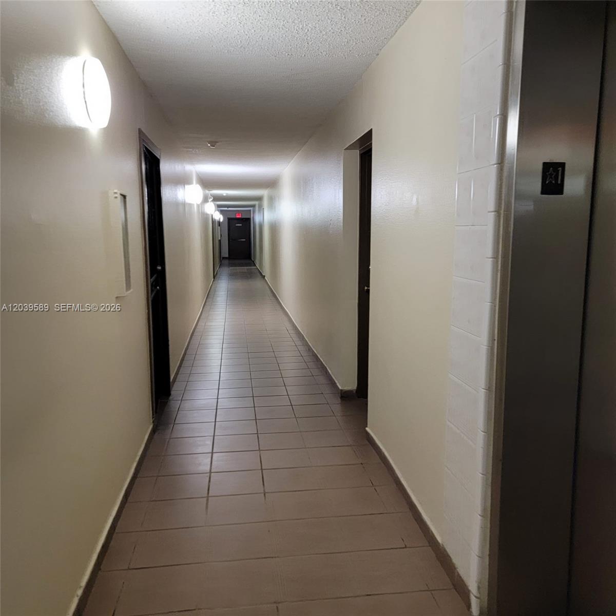 A long, narrow apartment hallway features beige walls, tiled flooring, and an elevator entrance — 4841 NW 7th St # 4, Miami FL 33126, MIAMI, FL