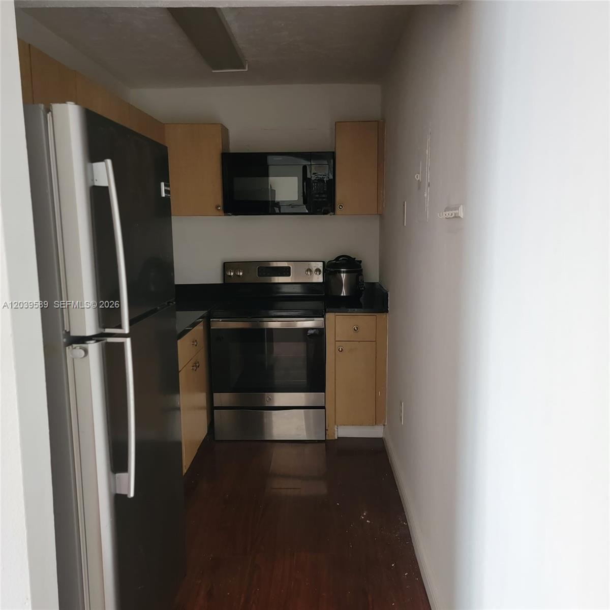 A galley kitchen features stainless steel appliances, light wood cabinets, and dark wood flooring — 4841 NW 7th St # 4, Miami FL 33126, MIAMI, FL