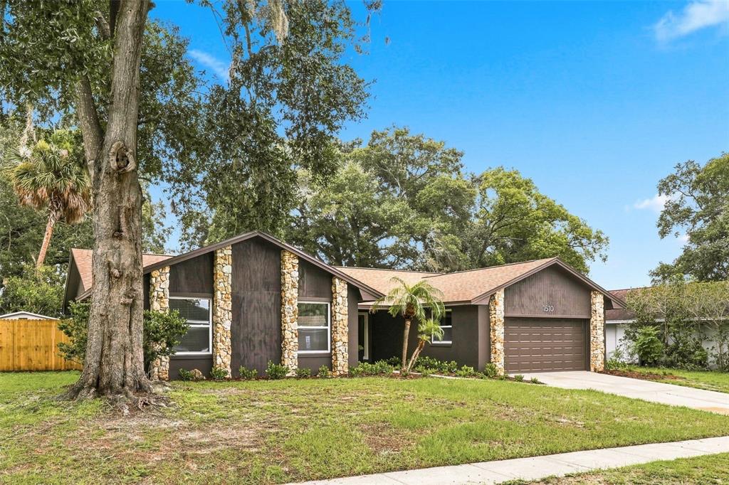 A single-story house with dark brown siding, stone accents, and a two-car garage — 1510 KENLYN DRIVE, LONGWOOD, FL