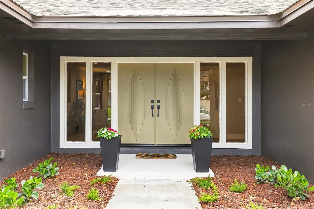 A front entrance features double doors with geometric detailing flanked by tall glass sidelights — 1510 KENLYN DRIVE, LONGWOOD, FL
