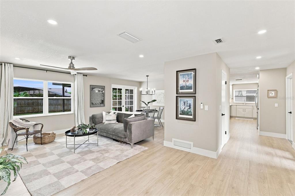 A living room with light wood floors, a gray sofa, and an adjacent dining area — 1510 KENLYN DRIVE, LONGWOOD, FL