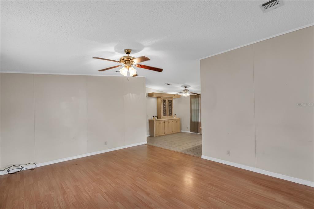 A living room with wood-look flooring, a ceiling fan, and an adjacent tiled dining area — 202 DANA COURT, KISSIMMEE, FL