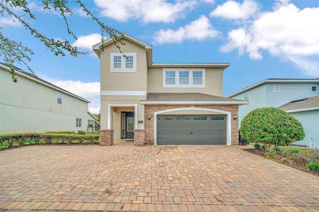 A two-story house with a stone-accented facade, a two-car garage, and a paved driveway — 400 BURMA STREET, KISSIMMEE, FL