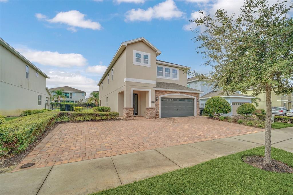 A two-story suburban house with a paved driveway, stone accents, and a two-car garage — 400 BURMA STREET, KISSIMMEE, FL