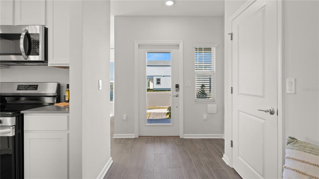 A kitchen area with white cabinets, stainless steel appliances, and a door leading outside — 6571 EASTWOOD CROSS DRIVE, ORLANDO, FL