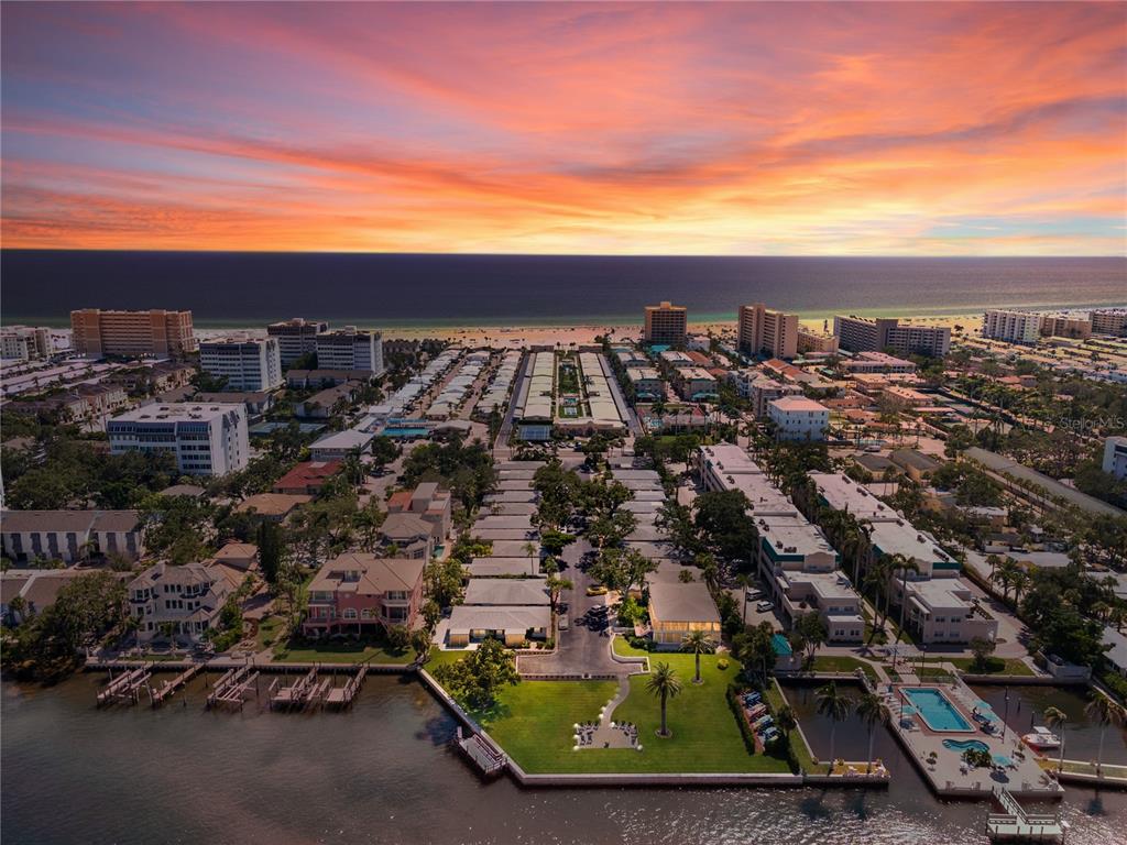 An aerial view shows a coastal residential complex with a sunset over the ocean — 6005 MIDNIGHT PASS ROAD UNIT N13, SARASOTA, FL