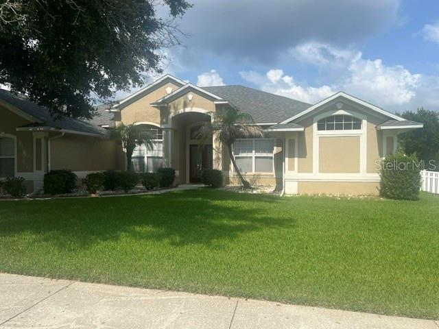 A tan single-story house with a gray shingled roof and a green lawn — 1206 BRENTWOOD DRIVE, CLERMONT, FL