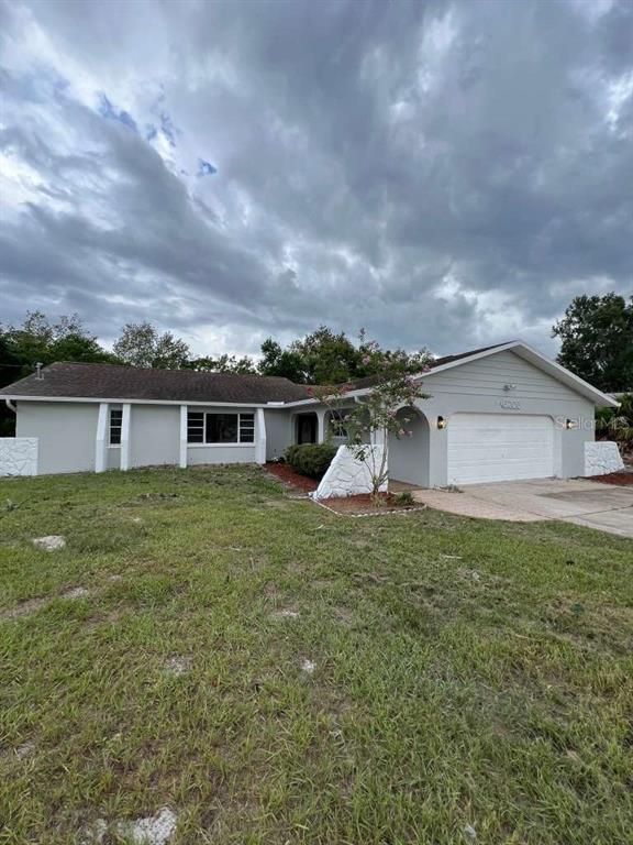 A single-story house with a white garage, gray siding, and a large front yard — 6206 DORSET ROAD, SPRING HILL, FL